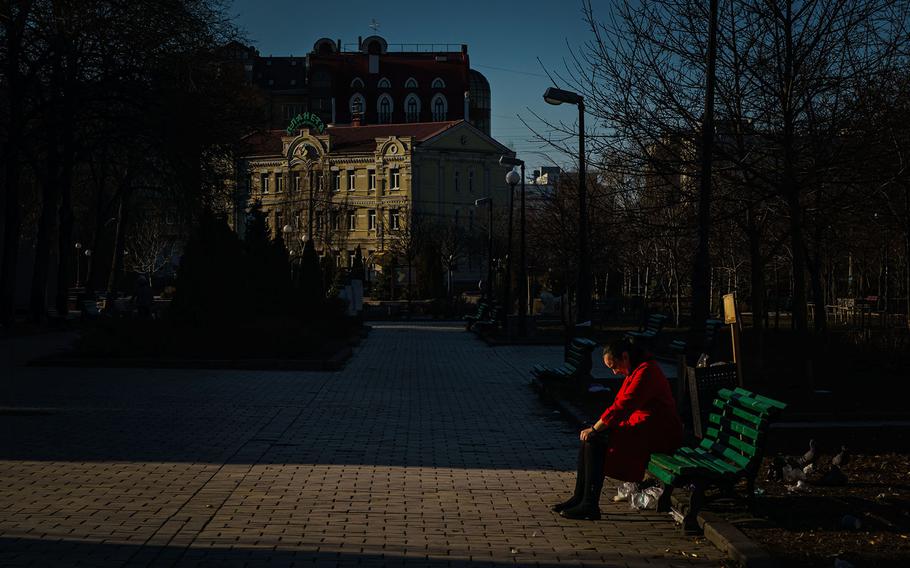 A woman sits alone in a park as the sun sets in Kyiv, Ukraine, Tuesday, March 15, 2022. 