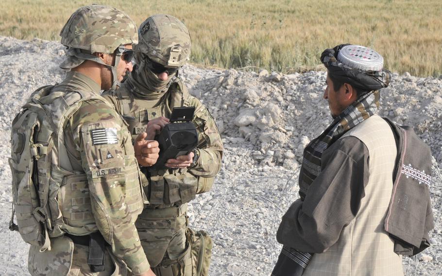 A linguist assists Pfc. John T. Roquemore, 2nd Battalion, 23rd Infantry Regiment, conduct biometric enrollments during a traffic checkpoint May 16, 2013, in Panjwai district, Kandahar province, Afghanistan. Human Rights Watch analysts now believe the Taliban may be using the U.S. military-collected data to track former Afghan soldiers.