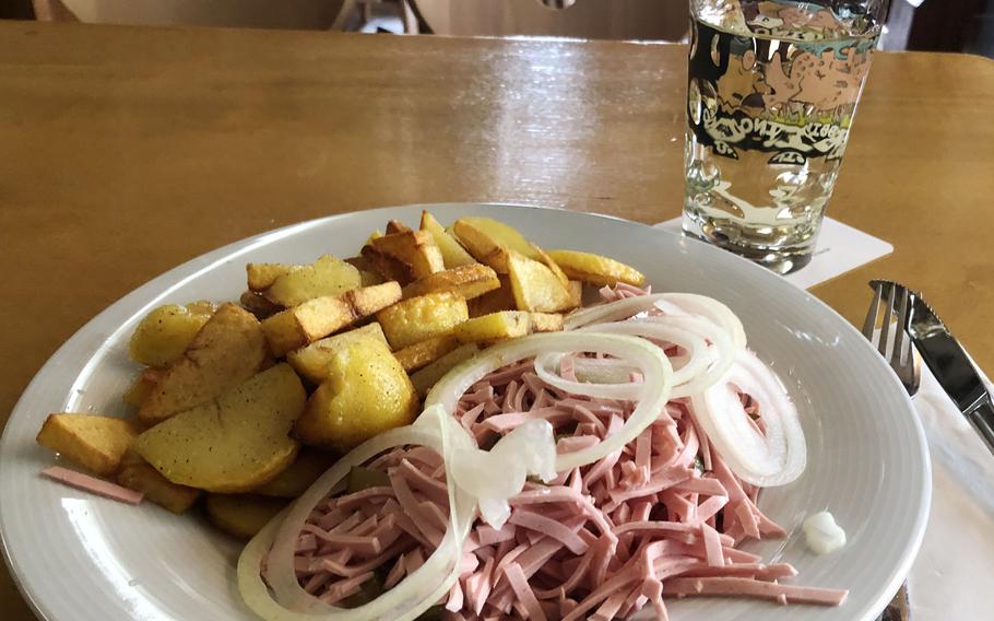 A wurstsalat, or sausage salad, served with roasted potatoes at the Wurst-Kuech in Kaiserslautern, Germany. It's made with sliced cold cuts and pickles in a vinegar dressing and is topped with onions.