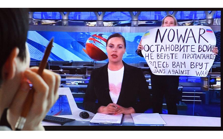 A woman looks at a computer screen watching a dissenting Russian Channel 1 employee entering Ostankino on-air TV studio during Russia’s most-watched evening news broadcast, holding up a poster which reads as “No War” and condemning Moscow’s military action in Ukraine in Moscow.