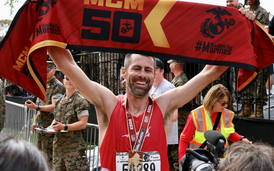 Calum Neff holds aloft the finish tape after winning the Marine Corps Marathon 50k race Sunday, Oct. 29, 2023, in Arlington, Va. Neff was timed in 2:55:57.