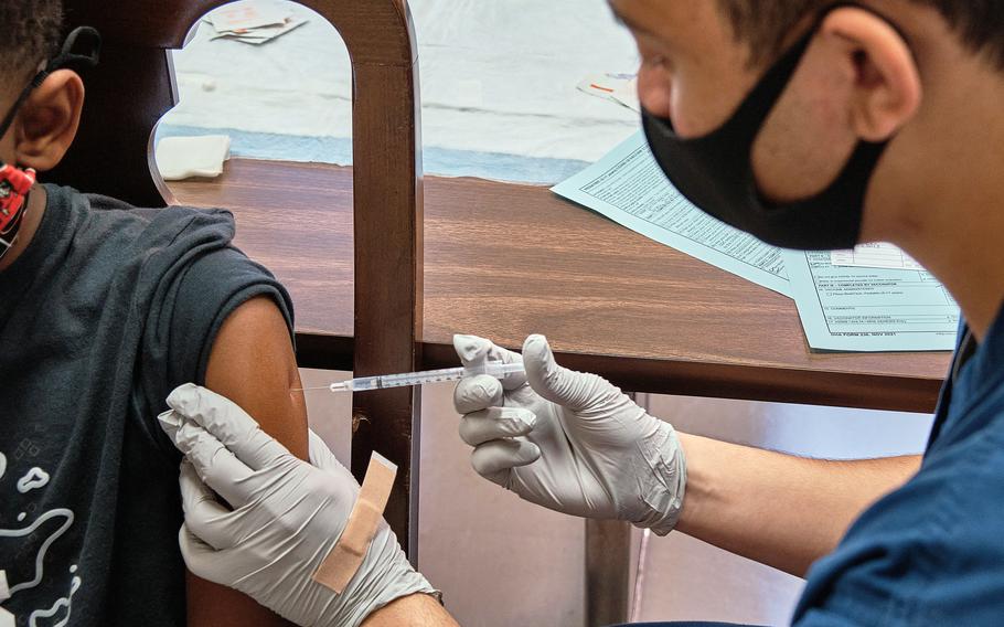 Petty Officer 3rd Class Keanu Baez administers the Pfizer COVID-19 vaccine to a child at Yokosuka Naval Base, Japan, Tuesday, Nov. 16, 2021. 