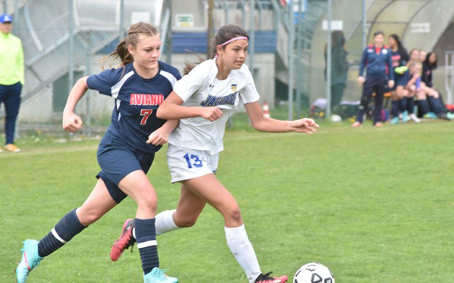 Aviano's Kylee Moncur tries to elbow her way to the ball past Sigonella's Ryleigh Denton in the Jaguars' 4-1 victory over the Saints on Saturday, April 15, 2023.