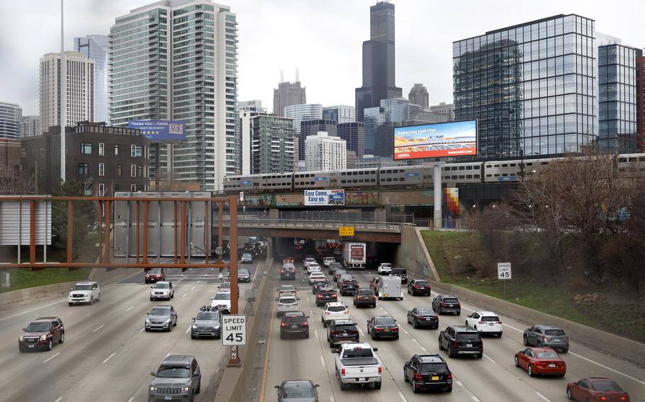 Traffic flows along Interstate 90 highway as a Metra suburban commuter train moves along an elevated track in Chicago on March 31, 2021.
