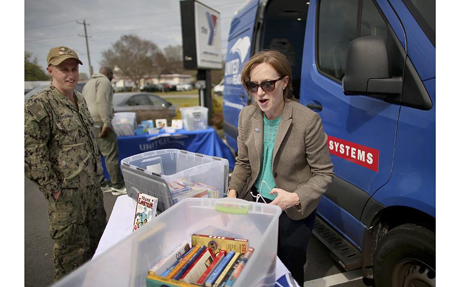 Program manager Lauren Steiner helps Petty Officer 2nd Class Tim Kershner select a book to read for his children. The United Through Reading van regularly stops at the Armed Services YMCA in Virginia Beach.