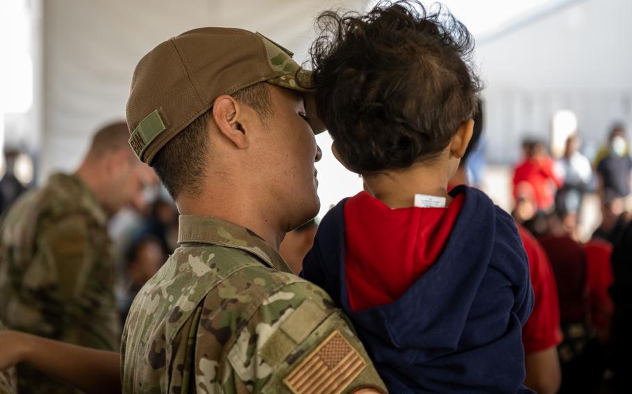 A Task Force Holloman Airman holds up an Afghan child during a performance by the U.S. Air Force Academy Winds musical ensemble at Aman Omid Village at Holloman Air Force Base, N.M., Oct. 12, 2021. 