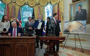 U.S. President Donald Trump at his desk in the Oval Office surrounded by lawmakers looking at an artist’s rendition of the Golden Dome missile system.
