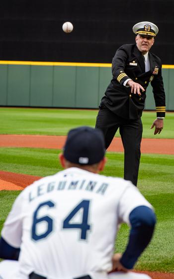 A sailor throws a baseball to a player