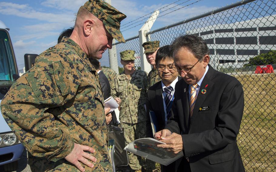 Okinawa Gov. Denny Tamaki inspects a coin he was given during a tour of Camp Kinser, Okinawa, Jan. 31, 2019.