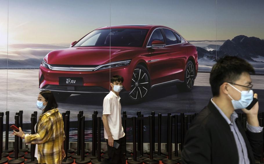 Visitors walk past an advertisement for the BYD Co. Han electric vehicle at the carmaker’s booth at the Auto Shanghai 2021 show in Shanghai, China, on Tuesday, April 27, 2021.