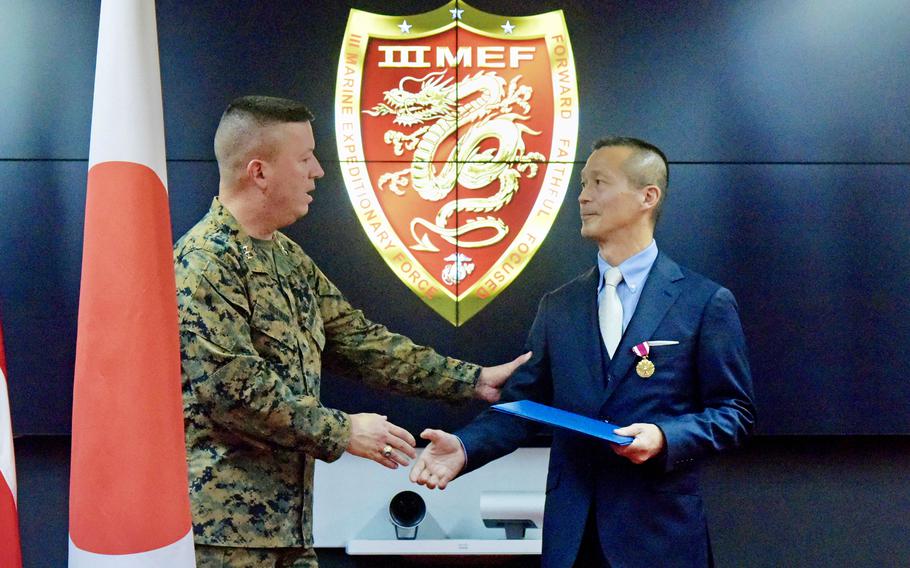 The commander of III Marine Expeditionary Force, Lt. Gen. James Bierman, presents the Meritous Service Medal to retired Col. Rikiya Kondo of the Japan Ground Self-Defense Force, at Camp Courtney, Okinawa, Jan. 6, 2023. 