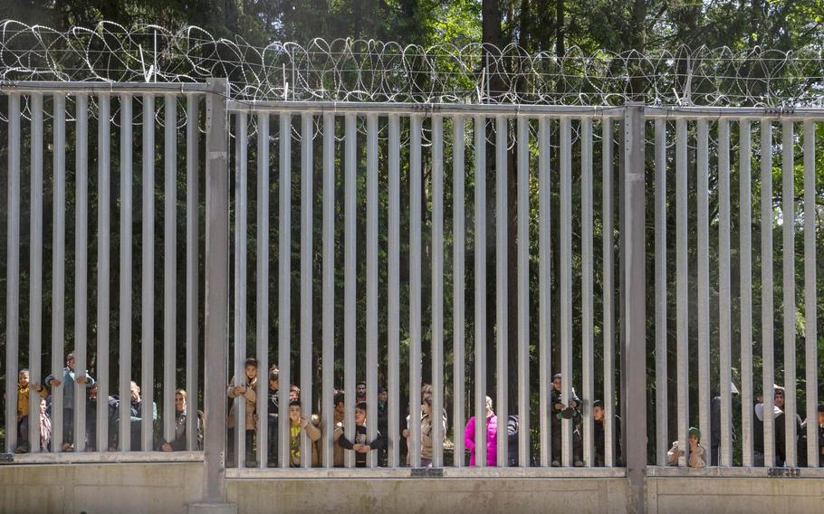 Members of a group of some 30 migrants seeking asylum look through the railings of a wall that Poland has built on its border with Belarus to stop massive migrant pressure, in Bialowieza, Poland, on May 28, 2023. Poland’s President Andrzej Duda said Thursday Sept. 14, 2023 he was awaiting the results of an investigation into allegations of a cash-for-visa migration scandal of the principally anti-migrant Polish government while the opposition was asking if government officials knew some of this European Union country visas were sold to terrorism suspects.