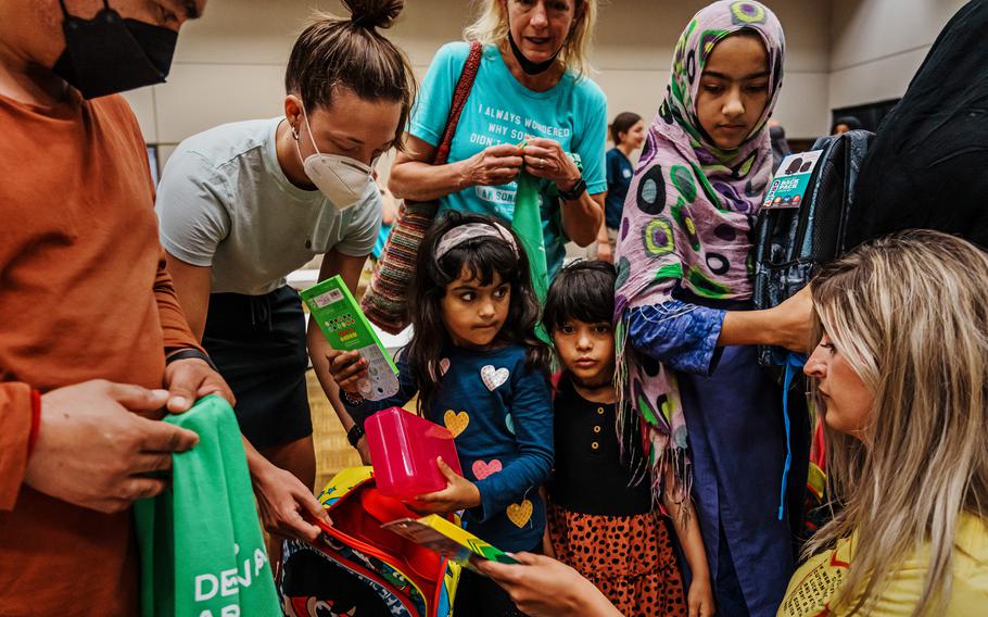 Rahmat Gul Safi, left, looks on as children, from left, Bus Bibi, 4, Zinab Safi, 3, and Shabo Gul, 8, collect free back-to-school supplies from members of Des Moines Refugee Support, a volunteer organization that is meeting the burgeoning needs of newly arrived Afghan refugees in Iowa, on Aug. 6, 2022. 