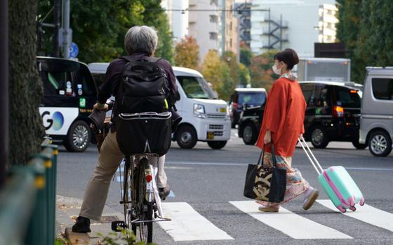 A cyclist waits for a traffic light to change on a busy street in Tokyo on Nov. 10, 2022.