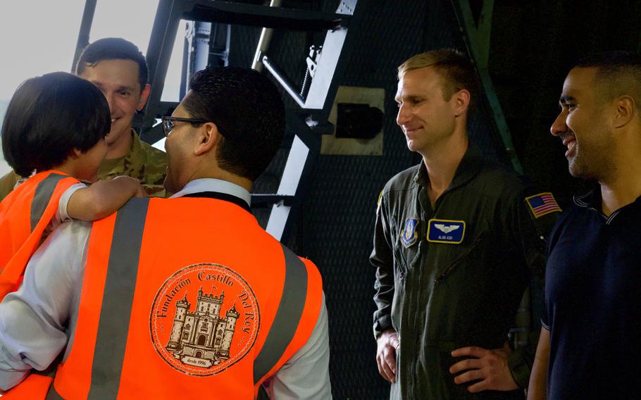 Airmen speak with people in orange vests.