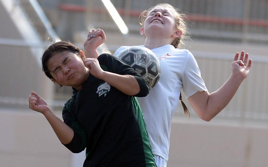 E.J. King's Madylyn O'Neill and Nagoya International's Julia Nagata try to play the ball off a corner kick during Friday's Western Japan Athletic Association girls soccer tournament. The Cobras won 8-0.