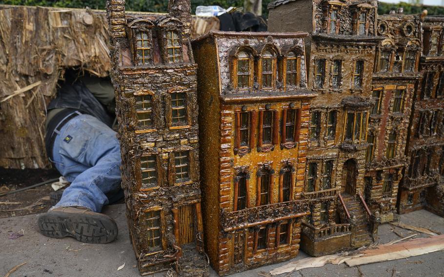 A man works around miniature brownstone buildings during the preparations for the annual Holiday Train Show at the New York Botanical Garden in New York, Thursday, Nov. 11, 2021. The show, which opens to the public next weekend, features model trains running through and around New York landmarks, recreated in miniature with natural materials. 