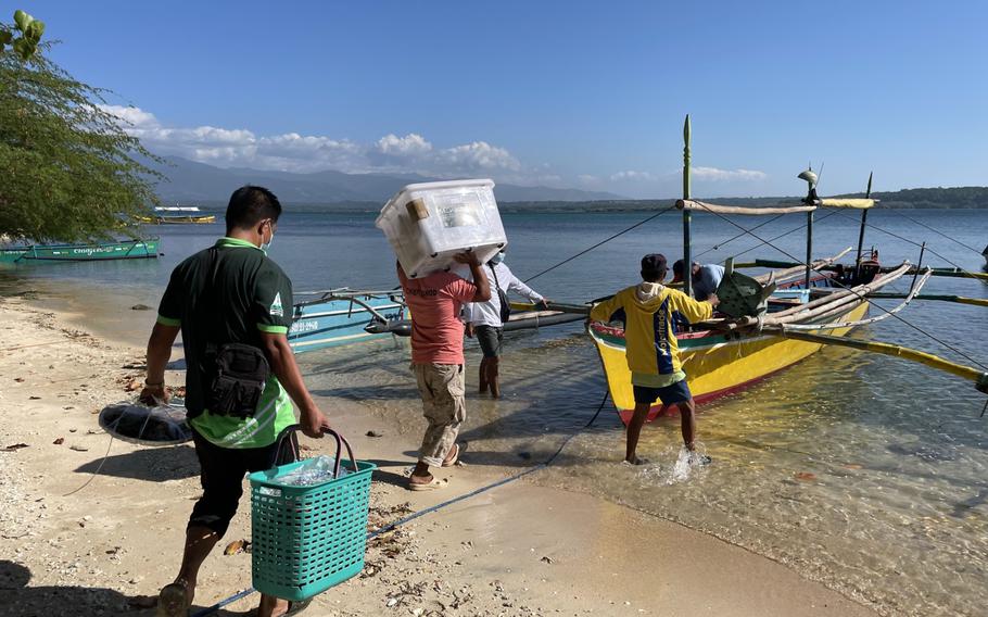 Staff members load Covid-19 vaccine equipment onto a boat during a vaccine drive in San Salvador, Philippines, on Jan. 11, 2022.