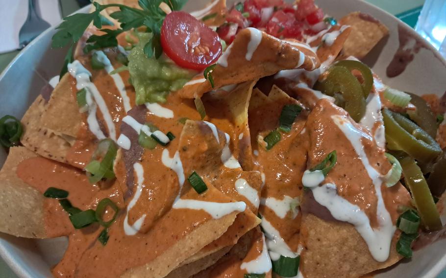 Nachos covered in a bean puree mixed with sour cream and topped with sliced tomatoes and jalapenos.