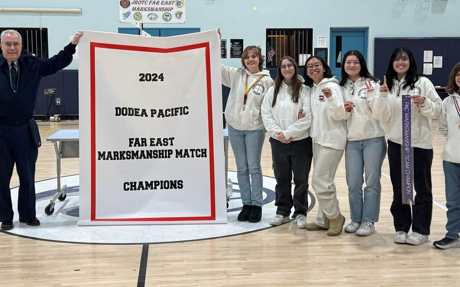 Matthew C. Perry's DODEA-Pacific marksmanship champion team, featuring Jessica Griffin, Autumn Hendra, Jasmine Griffin, Maya Slaughter, Madiline Theberge and Siyennah Igmen with the championship banner.