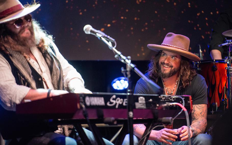 Scooter Brown, right, looks on as his bandmate Donnie Reis plays keyboard during a War Hippies performance March 9, 2023, at MadLife Stage & Studios in Woodstock, Ga., just north of Atlanta. Both musicians are combat veterans who served in Iraq.