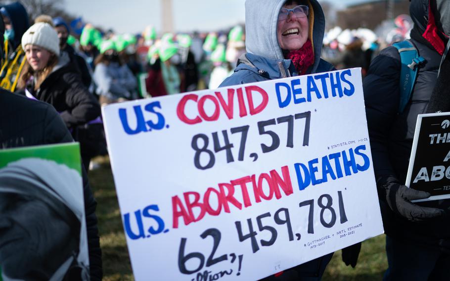 Melanie Frei, 66, of Tomah, Wis., holds a sign comparing covid deaths with abortion deaths at the March for Life Rally in Washington on Jan. 21, 2022.