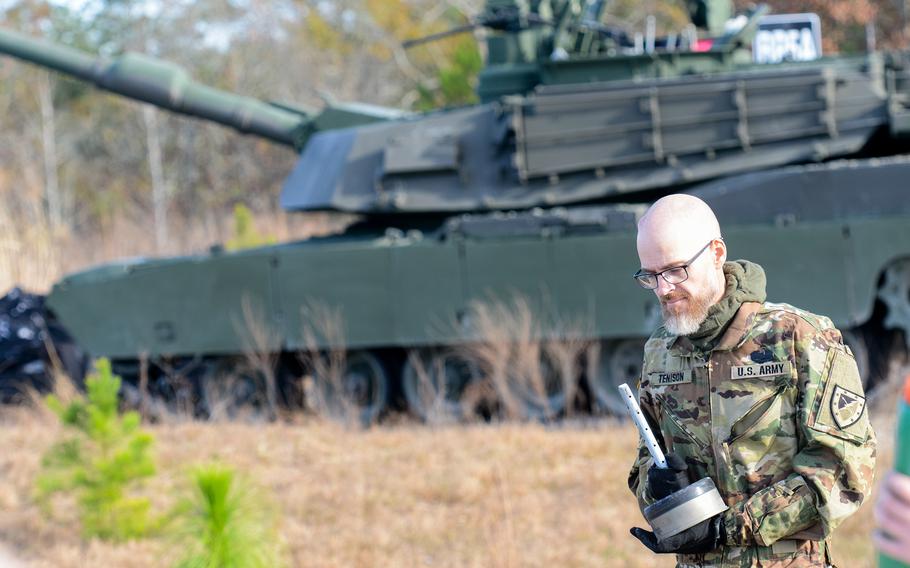 Jay Tenison, a former Army tanker who served in Iraq and was diagnosed in 2022 with terminal cancer, holds a shell that he shot from an M1A2 Abrams tank at Fort Moore, Ga., on Dec. 5, 2023. Tenison lobbied the Army to shoot a tank one more time before he died. 