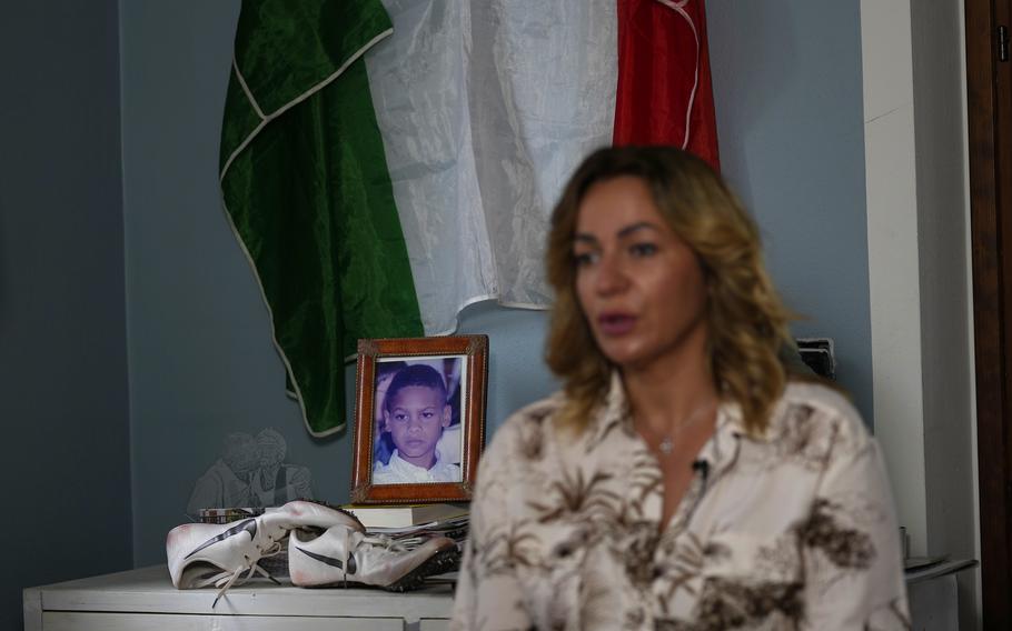 Viviana Masini, mother of Italy's Lamont Marcell Jacobs, shows a corner in her home, devoted to the winner of the 100 meters at the Tokyo Olympics, with an old pair of running shoes, a photo of him as a child and the Italian flag, in Manerba del Garda, Italy, Monday, Aug. 2, 2021.