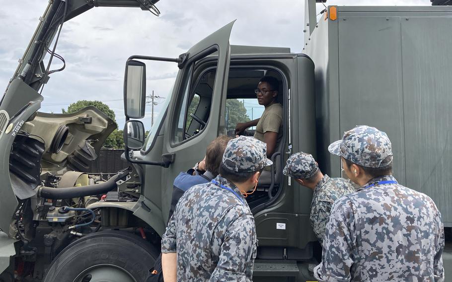 Airman 1st Class Devin Downs gives Japanese airmen a rundown on a vehicle used to remove ice from aircraft at Yokota Air Base, Japan, Thursday, Sept. 7, 2023.
