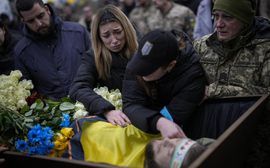 Widow Anastasia Ohrimenko, left, mourns with Anya Korostenska over the body of her fiance Oleksiy Zavadskyi, a Ukrainian serviceman who died in combat on Jan. 15 in Bakhmut, during his funeral in Bucha, Ukraine, Thursday, Jan. 19, 2023.