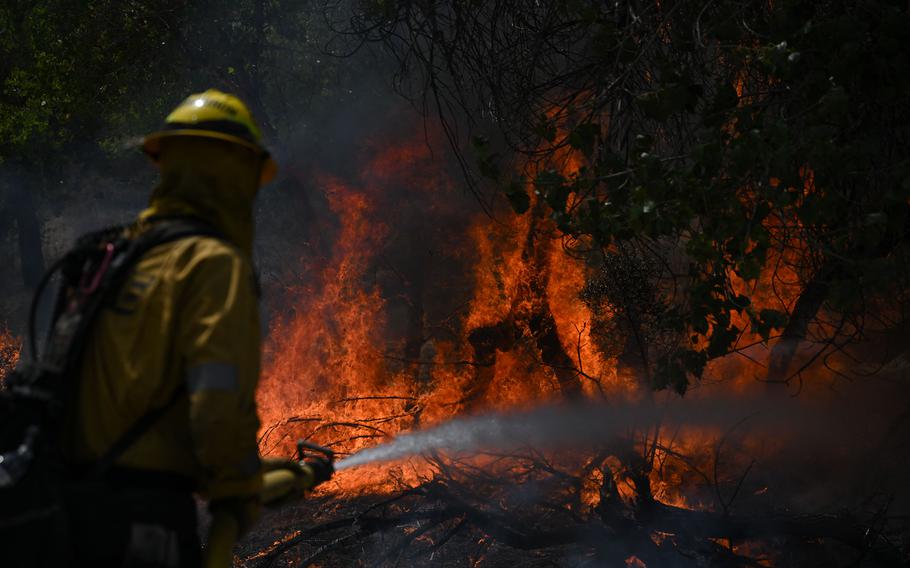 A firefighter sprays water on flames as he works to contain wildfire along Bautista Canyon Road during the Fairview Fire in the San Bernardino National Forest near Hemet, Calif., on Sept. 7, 2022.