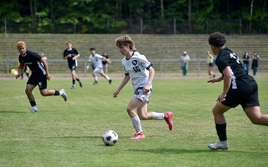 AFNORTH striker Patrick Stevens dribbles toward the Alconbury net as Dragon defenders Taye Vickerstaff, left, and Luis Alejandro Diez chase him during a Division III semifinal match at the 2025 DODEA European championships on May 21, 2025, at Rothenborn Stadion in Landstuhl, Germany.