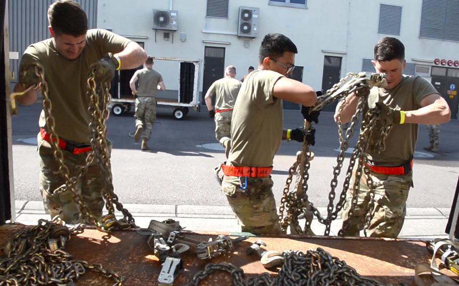 Capt. Trevor Chasteen, left, Senior Airman Gerald Dinio, center, and Airman 1st Class Mitchell Lagrange load chains onto a cart after carrying them around 30 feet during the endurance event of the 721st Aerial Port Squadron Multi-Capable Airmen Rodeo at Ramstein Air Base, Germany, July 23, 2021.