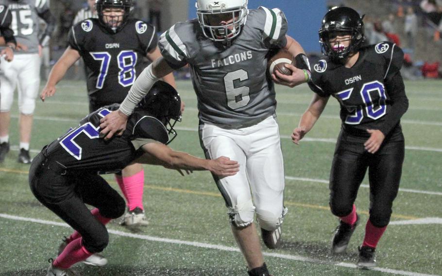 Singapore quarterback Heathe Billingslea makes his way between Osan's Ethan DiStefano and Owen Carroll.