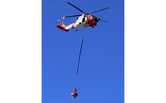 A U.S. Coast Guard helicopter carries a large red buoy from the beach at the Cape Lookout National Seashore. Buoys of this size are used to mark the entrances to inlets.