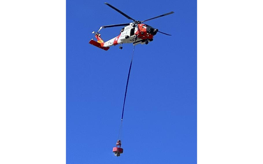 A U.S. Coast Guard helicopter carries a large red buoy from the beach at the Cape Lookout National Seashore. Buoys of this size are used to mark the entrances to inlets.