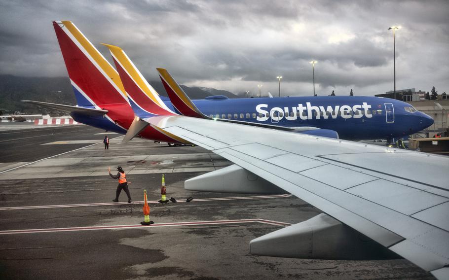The wing of an airplane extends over a runway as another plane with Southwest branding is parked farther away.