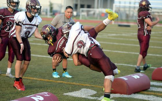 Perry's Ethan Mercado wrestles ballcarrier Adrian Isaac-Otero down during a tackling drill.