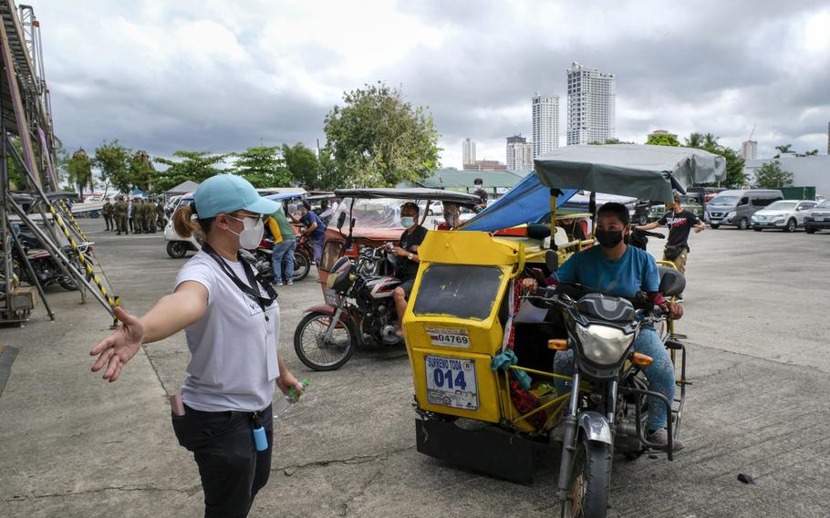 A health worker directs motorcycle taxi drivers at a COVID-19 drive-thru vaccination site set up at the Philippine International Convention Center in Manila, Philippines, on June 22, 2021.