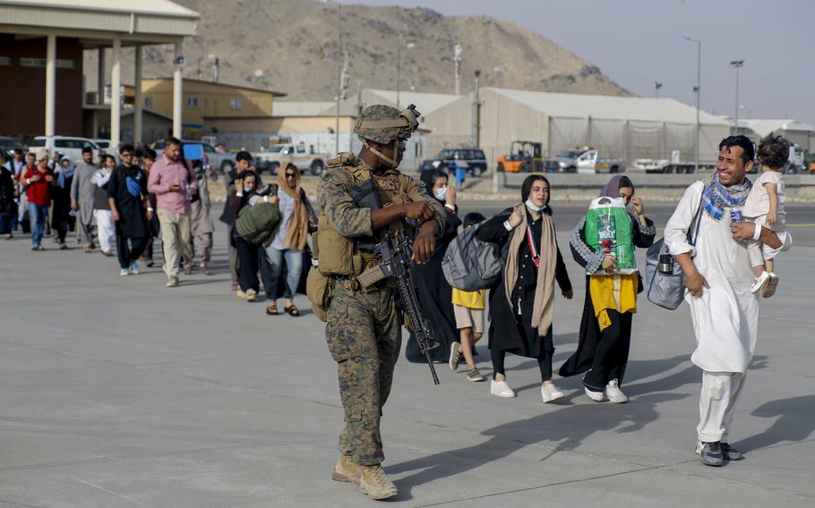 A U.S. Marine assigned to 24th Marine Expeditionary Unit escorts evacuees during an evacuation at Hamid Karzai International Airport, Afghanistan, Aug. 18, 2021. 