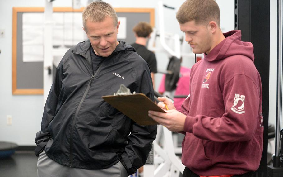 Fourth-year Osan football coach Jerome Learman, left, and assistant Jacob Callison go over personnel during an indoor workout.