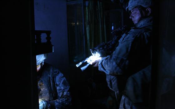 Arab Jabour district, Iraq, Jul. 5, 2007: Pvt. Erik Stroehlein, 22, Bennington, Vt., holds a light for Capt. Eric Melloh, 30,  of Huntsville, Texas, during the search of the home of a man suspected of helping insurgents direct mortar fire at Forward Operating Base Murray in Iraq’s Arab Jabour district southeast of Baghdad. Both men are from Company A, 1-30th Infantry, 3rd Infantry Division based at FOB Murray. 

See more photos and read the story here.
https://www.stripes.com/migration/stopping-insurgents-before-they-hit-baghdad-1.migrated

META TAGS: Operation Iraqi Freedom, War on Terror, U.S. Army, Company A, 1-30th Infantry, 3rd Infantry Division

