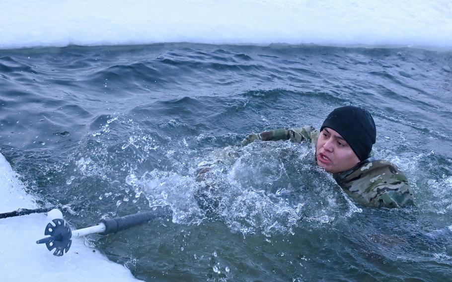 A soldier from Fort Wainwright, Alaska, in December 2023 works his way out of “The Hole,” an icy water hole that’s part of a competition among soldiers of the 1st Brigade of the 11th Airborne Division.