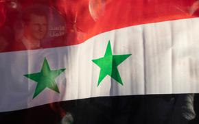 In this May 23, 2021, file photo, the Syria national flag is displayed at a gathering at Omayyid Square in the Syrian capital Damascus, Syria. 