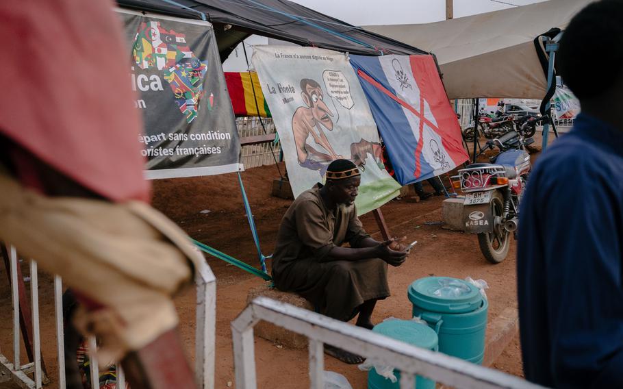 A man sits in front of anti-France banners in Niamey. 