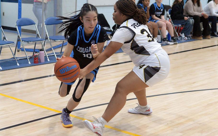 Osan's Jonessa Jones drives against Humphreys' Nyomi Peoples during Friday's DODEA-Korea girls basketball game. The Blackhawks won the Korea inter-division battle 51-17, handing the Cougars their first loss in eight games.