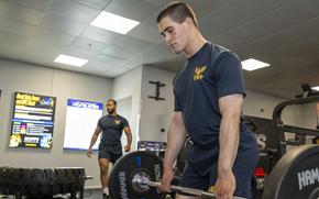 Sailors lift weights Aug. 14, 2025, during a ceremony for the opening of the upgraded gym at Naval Support Activity Souda Bay, Greece. The nearly $700,000 renovation included the addition of a zone featuring a range of strength-training equipment.
