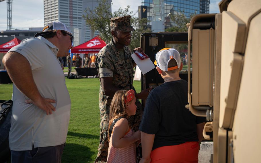 A Marine shows children a HUMMVEE.