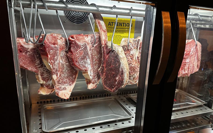 Dry-aged steaks hang from hooks just inside the entrance of the Casa do Brasil steakhouse in Vilseck, Germany.