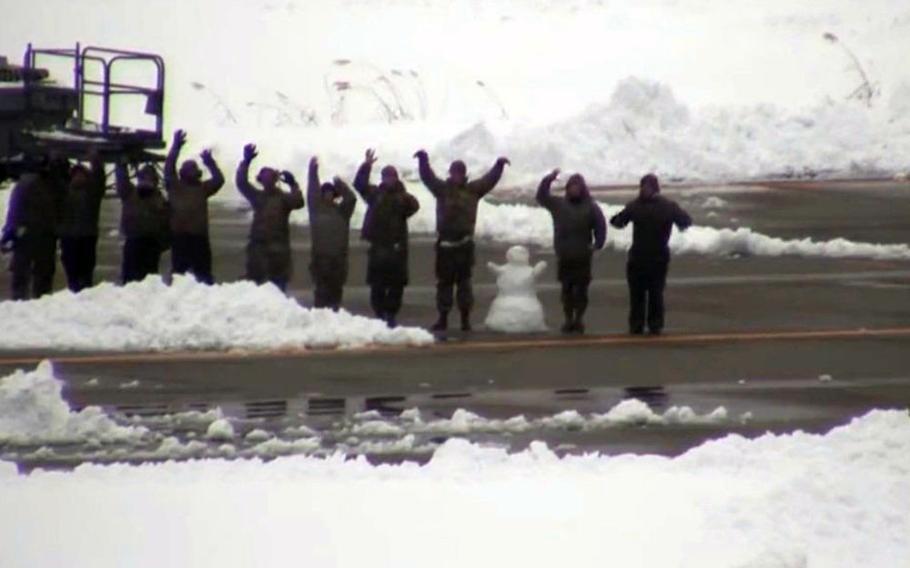 U.S. airmen wave at Aomori Airport, Japan, after repairing an F-16 Fighting Falcon that landed there because of an inflight emergency that forced the pilot to drop the jet's external fuel tanks. 